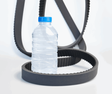 Bottle unscramblers: Belts lying on white floor around plastic bottle